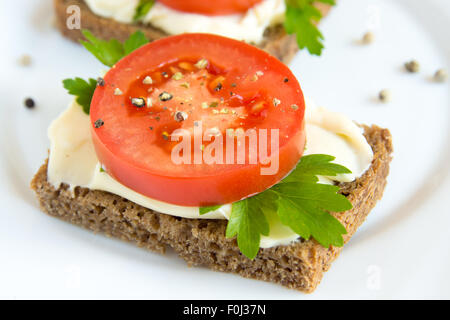 Sandwich mit Tomaten, Frischkäse, Petersilie und Pfeffer auf weißen Teller Stockfoto