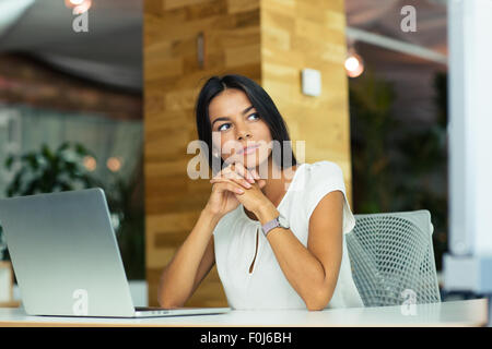 Porträt von nachdenklich Geschäftsfrau am Tisch im Büro sitzen und wegsehen Stockfoto