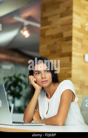 Porträt von nachdenklich Geschäftsfrau am Tisch im Büro sitzen und wegsehen Stockfoto