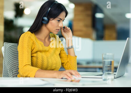 Porträt von lässig Geschäftsfrau im Kopfhörer mit Laptop im Büro Stockfoto