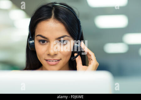 Glücklich Geschäftsfrau auf Laptop mit Kopfhörer im Büro arbeiten Stockfoto
