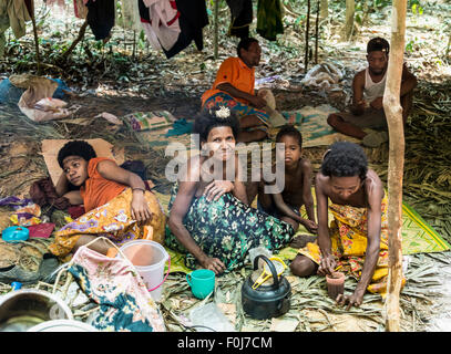 Männer, Frauen und Kinder des Stammes Orang Asil sitzen unter Planen im Dschungel, native, indigene Völker Stockfoto