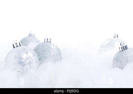 Silberne Weihnachtskugeln auf eine weiche federleichte Oberfläche mit einem weißen Hintergrund. Stockfoto