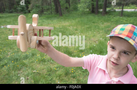 Kinderspiel mit einem hölzernen Flugzeug in den Bergen. Wald Stockfoto