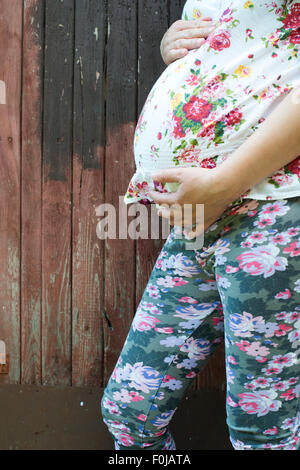 Schwangere Frauen vor alten roten Holzwand. Stockfoto