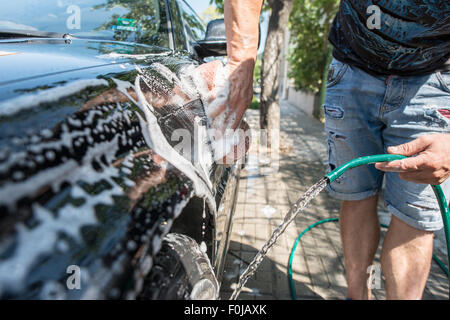 Männer waschen sein Auto. Schließen Sie Schlauch Stockfoto