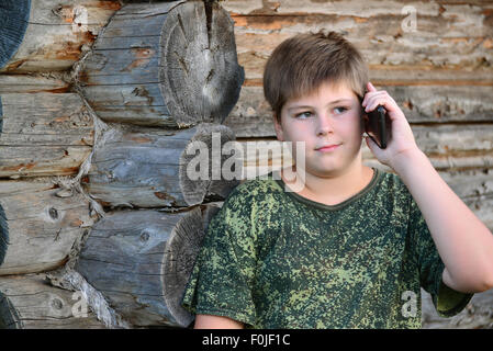 Teenager-Jungen sprechen über Handy-Stellung von Holzwand Stockfoto