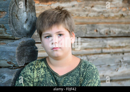 Teen Boy in Tarnung steht in der Nähe von Holzwand Stockfoto