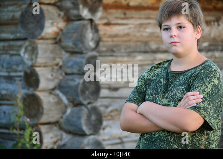 Teen Boy in Tarnung steht in der Nähe von Holzwand Stockfoto