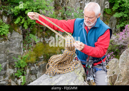 Aktive Senioren senior Kletterer Auspacken ein kletterseil oben auf einem Felsen zu klettern. Snowdonia, North Wales, UK, Großbritannien Stockfoto