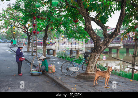 Hoi an Vietnam Street, Blick entlang des Flusses Thu Bon in Hoi an auf einen Straßenverkäufer, der sich mit einem Kunden, Hoi an Old Town, Zentralvietnam, unterhält. Stockfoto