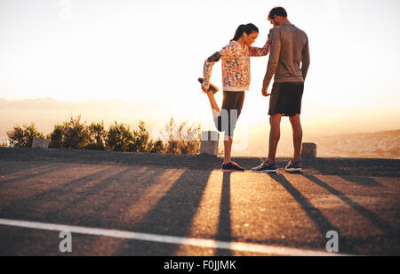 Im Freien Schuss von Fit junge Jogger dehnen vor einem Lauf zusammen morgen. Junger Mann stehen und die Frau ihre Beine Stockfoto