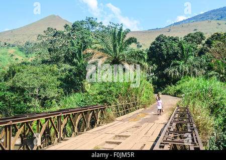 Mädchen tragen einen Eimer auf dem Kopf in Kamerun zu Fuß auf einer alten kolonialen Brücke Stockfoto