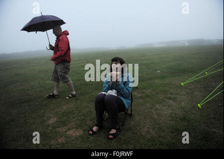 Mann und Frau, die versucht, Suppper auf einem Campingkocher in Cornwall in Wind und Regen zu kochen Stockfoto