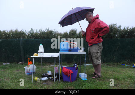 Mann und Frau, die versuchen, Suppper auf einem Campingkocher in Cornwall im Wind und Regen zu kochen Stockfoto