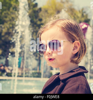 Schöne kleine Mädchen mit Sonnenbrille. Das Bild ist getönt. Stockfoto