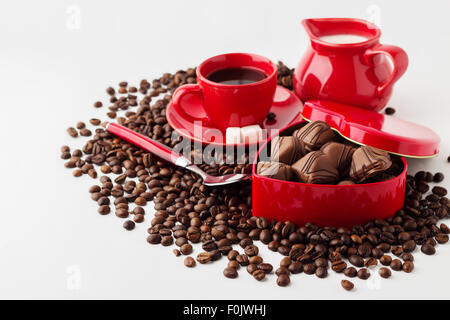 Tasse Kaffee, Milch und eine Box (Herzform) mit Schokolade auf die Kaffeebohnen. Isoliert auf weißem Hintergrund. Stockfoto