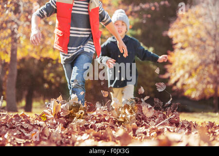 Jungen im Herbstlaub laufen Stockfoto