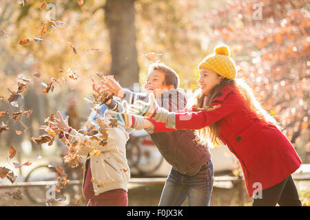 Jungen und Mädchen fangen Herbstlaub Stockfoto