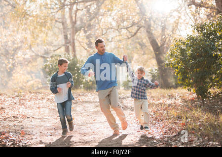 Verspielte Vater und Söhne auf Trail im Wald laufen Stockfoto