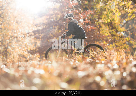 Jungen Fahrrad fahren in Wäldern mit Herbst Blätter Stockfoto