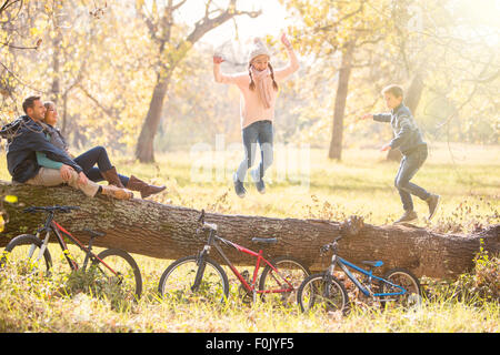 Familie auf umgestürzten Baumstamm im herbstlichen Wälder spielen Stockfoto