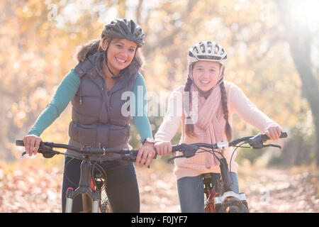 Porträt des Lächelns, Mutter und Tochter mit dem Mountainbike im Wald Stockfoto