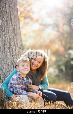 Porträt, Lächeln, Mutter und Sohn am Baumstamm im herbstlichen Wälder Stockfoto