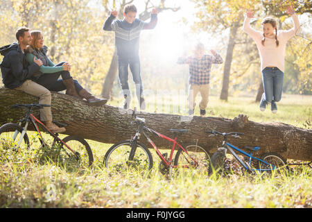 Familie auf umgestürzten Baumstamm mit Fahrrädern im Wald spielen Stockfoto