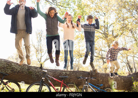 Begeisterte Familie springen von umgestürzten Baumstamm über Fahrräder Stockfoto