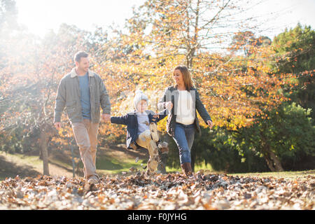 Familie Hand in Hand und Wandern im Herbstlaub Stockfoto