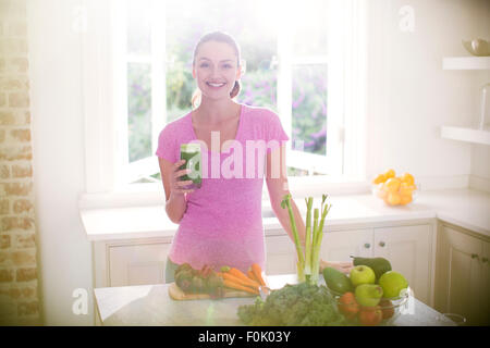 Porträt lächelnde Frau trinken grünen Smoothie in Küche Stockfoto
