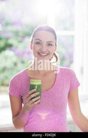 Porträt lächelnde Frau trinken grünen smoothie Stockfoto