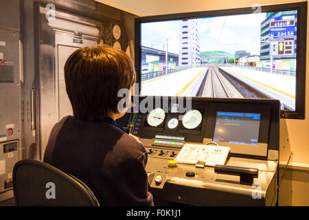 Shinkansen Museum, Nagoya. Blick über die Schulter der Kaukasischen junge Kind 10-12 Jahre alte, sitzen im Control Panel und ein Bildschirm in Train Simulator. Stockfoto