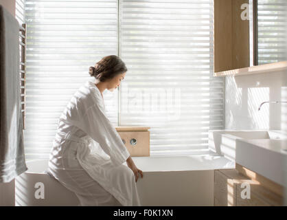 Frau im Bademantel zeichnen ein Bad in der Badewanne in Luxus-Badezimmer Stockfoto