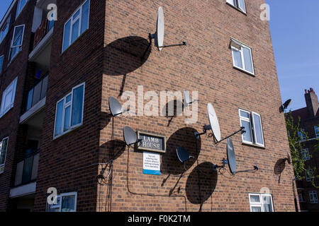 Satellitenschüsseln an der Seite von einem Wohnblock in einem South London Anwesen. Stockfoto