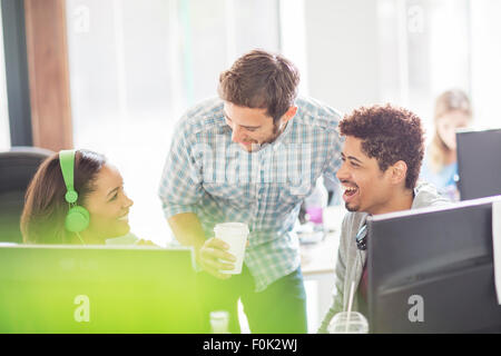 Kreative Geschäftsleute mit Kopfhörer und Kaffee Lachen am Computer Stockfoto Kreative Geschäftsleute mit Kopfhörer und Kaffee Lachen am Computer Stockfoto