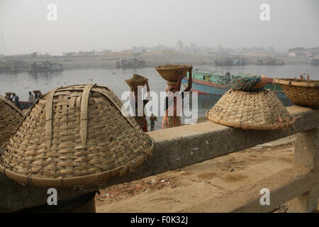 Männliche und weibliche Arbeiter tragen schwere Lasten von Sand auf ihre Köpfe in die Bank von Turag River bei Gabtoli in Dhaka ausgeglichen. Stockfoto