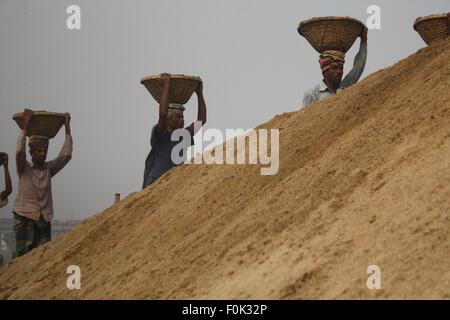 Männliche und weibliche Arbeiter tragen schwere Lasten von Sand auf ihre Köpfe in die Bank von Turag River bei Gabtoli in Dhaka ausgeglichen. Stockfoto