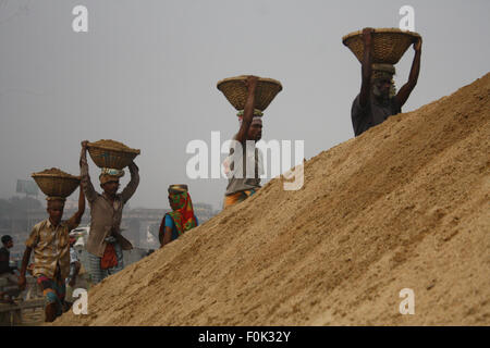 Männliche und weibliche Arbeiter tragen schwere Lasten von Sand auf ihre Köpfe in die Bank von Turag River bei Gabtoli in Dhaka ausgeglichen. Stockfoto