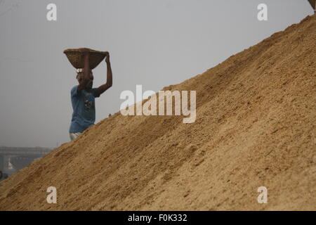 Männliche und weibliche Arbeiter tragen schwere Lasten von Sand auf ihre Köpfe in die Bank von Turag River bei Gabtoli in Dhaka ausgeglichen. Stockfoto