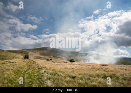 Fahrzeuge der Arbeitnehmer brennen Gräser auf die Mauren über Glossop in Derbyshire als Teil eines Managementplans Moorland. Stockfoto