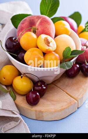 Frisches Steinobst Kirschen Pfirsiche Pflaumen in Schüssel weiß Stockfoto