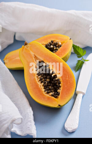 Schneiden von exotischen Früchten Papaya auf a blaue Tabelle Stockfoto