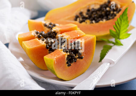 Schneiden von exotischen Früchten Papaya auf a blaue Tabelle Stockfoto