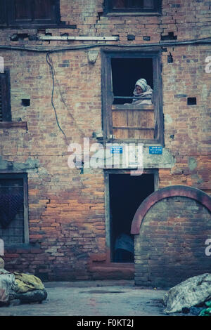 Altbau im historischen Zentrum von Bhaktapur mit Greis Blick durch das Fenster. UNESCO-Weltkulturerbe. Stockfoto