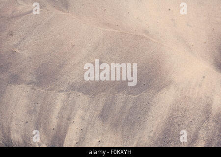 Lila geschwungenen Strand Muster an einem Strand. Diese bunten Mustern am Strand entstehen durch die Wellen mit Sand und schwarzen Schlamm. Stockfoto