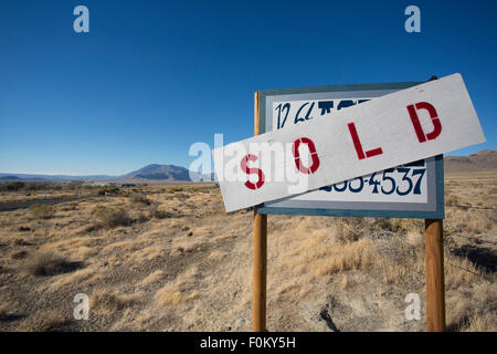 Ein Zeichen für den Verkauf ein Grundstück mitten im nirgendwo in Nevada Staaten mit einem klaren und blauen Himmel im Hintergrund Stockfoto