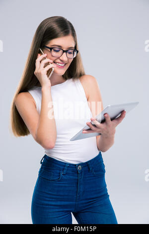 Porträt von glücklich weibliche Teenager am Telefon sprechen und Tablettcomputer isoliert auf weißem Hintergrund Stockfoto