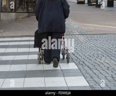 Ältere Frau mit Walker Kreuzung Straße am Zebrastreifen in Stadt Stockfoto
